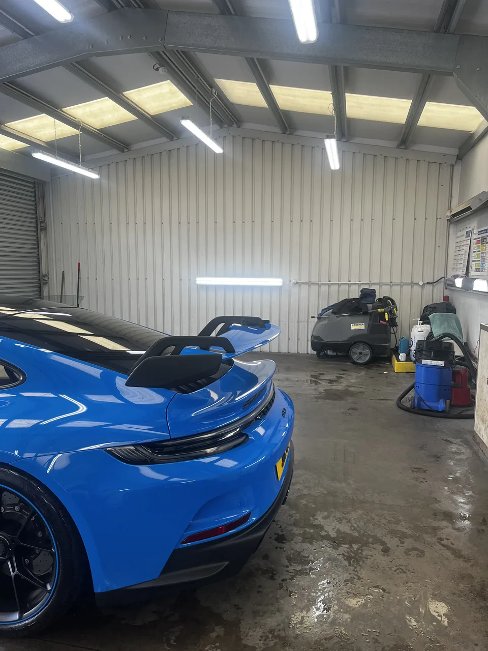 Blue Porsche rear and rear wing in a valeting workshop